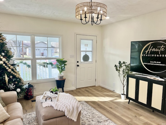 foyer with light wood-type flooring, a textured ceiling, and an inviting chandelier