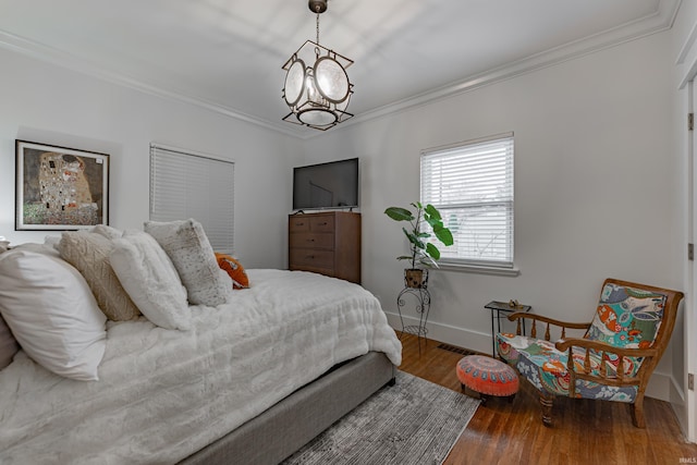 bedroom featuring hardwood / wood-style flooring, crown molding, and an inviting chandelier