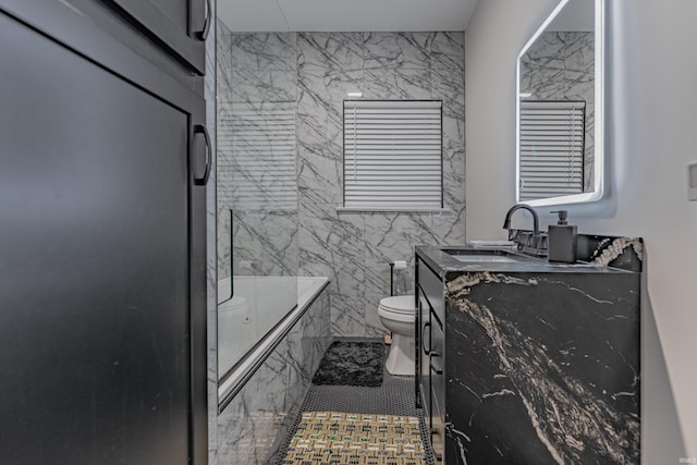 full bathroom featuring tile patterned flooring, enclosed tub / shower combo, toilet, vanity, and tile walls