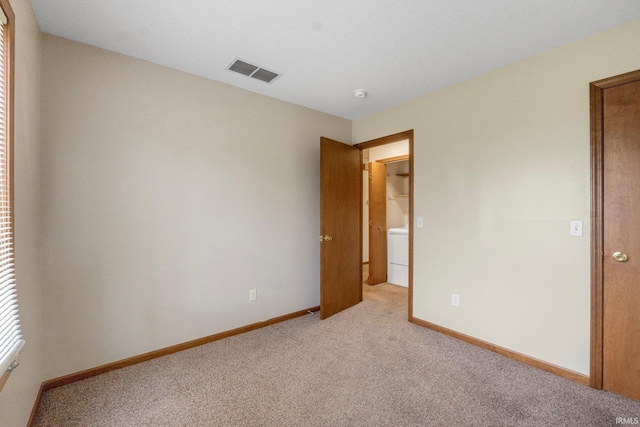 unfurnished bedroom featuring light colored carpet and washer / clothes dryer