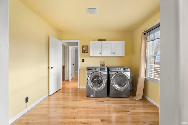 washroom featuring cabinets, washer and dryer, and light wood-type flooring