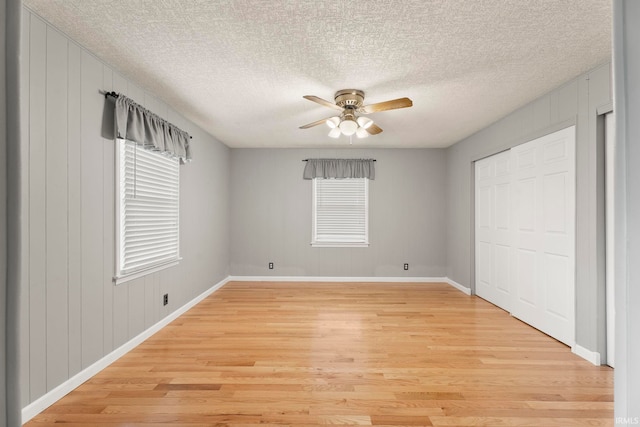 unfurnished bedroom featuring multiple windows, a textured ceiling, light hardwood / wood-style flooring, and ceiling fan