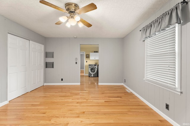 unfurnished bedroom featuring ceiling fan, light hardwood / wood-style floors, washer / dryer, and a closet