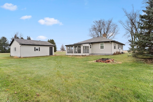 back of house with a sunroom, a yard, and a fire pit