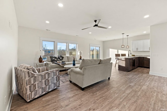 living room featuring light hardwood / wood-style floors, ceiling fan, and sink