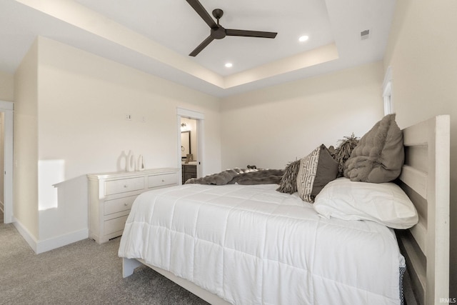 carpeted bedroom with connected bathroom, a raised ceiling, and ceiling fan