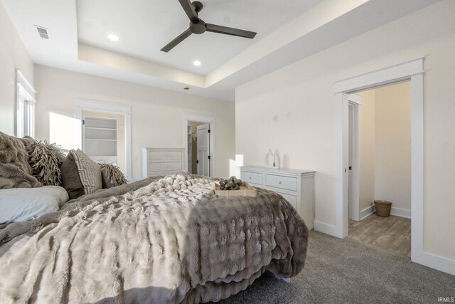 bedroom featuring ceiling fan, light colored carpet, a spacious closet, and a tray ceiling