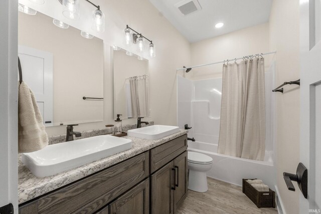 full bathroom with wood-type flooring, vanity, toilet, and shower / bath combo with shower curtain