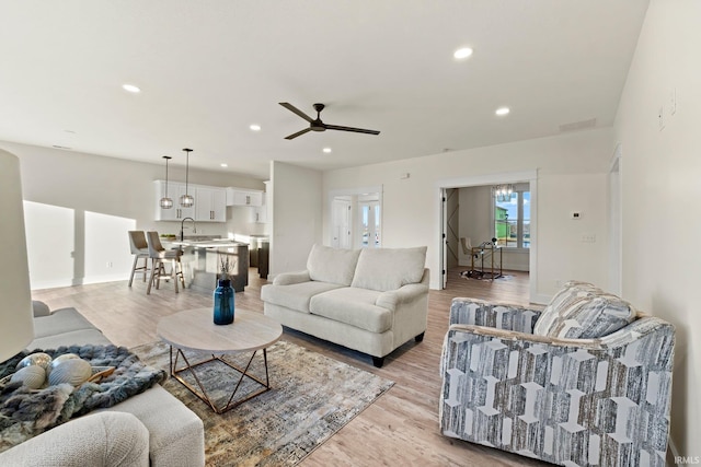 living room with ceiling fan, light wood-type flooring, and sink