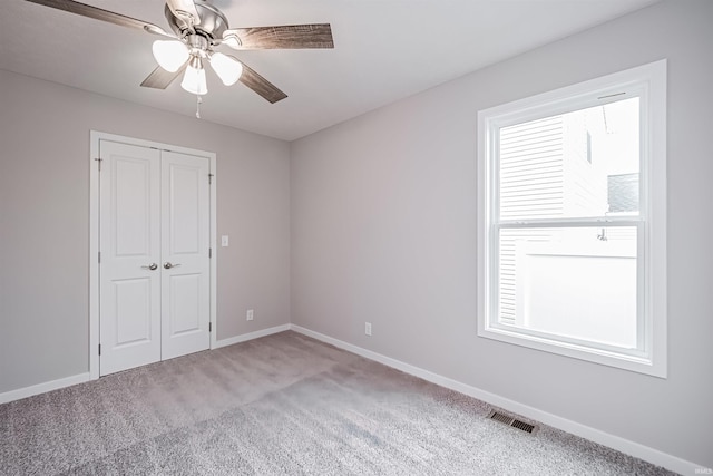 unfurnished bedroom featuring carpet flooring, multiple windows, and ceiling fan