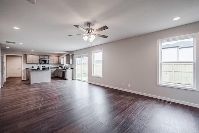 unfurnished living room with dark hardwood / wood-style flooring, ceiling fan, and a healthy amount of sunlight