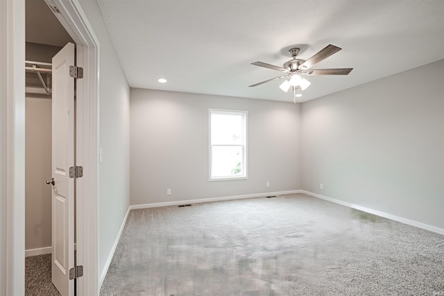 unfurnished bedroom featuring carpet flooring, ceiling fan, a closet, and a spacious closet