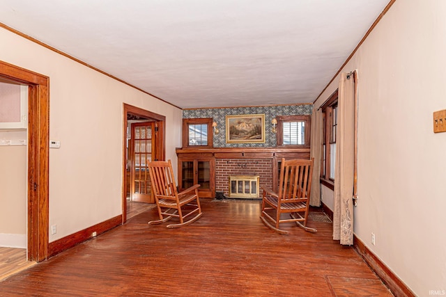 sitting room featuring hardwood / wood-style floors, ornamental molding, and a brick fireplace