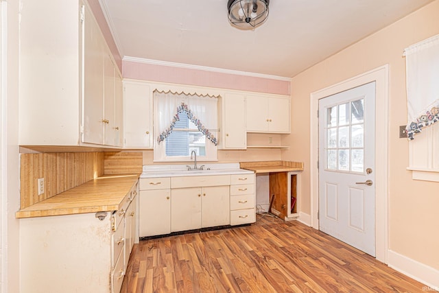 kitchen featuring light hardwood / wood-style floors, white cabinetry, crown molding, and sink