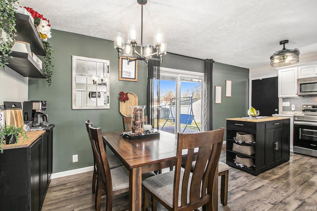 dining area featuring a textured ceiling, dark wood-type flooring, and a notable chandelier