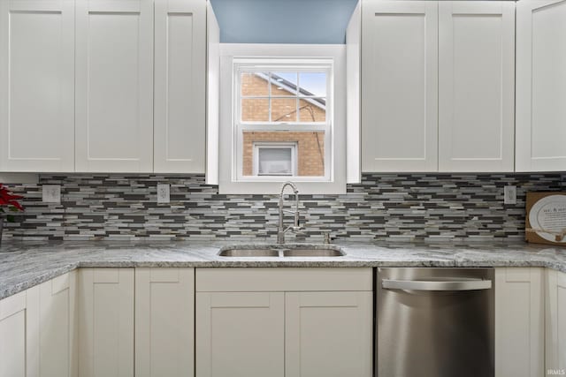 kitchen featuring white cabinetry, dishwasher, light stone countertops, sink, and backsplash