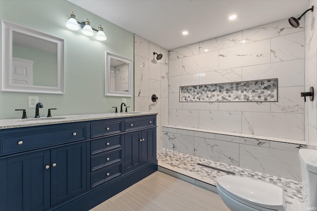 bathroom with vanity, toilet, and tiled shower