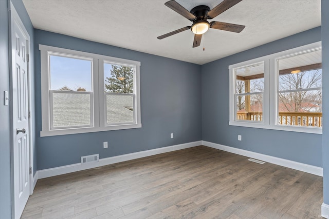 empty room with ceiling fan, light wood-type flooring, and a wealth of natural light