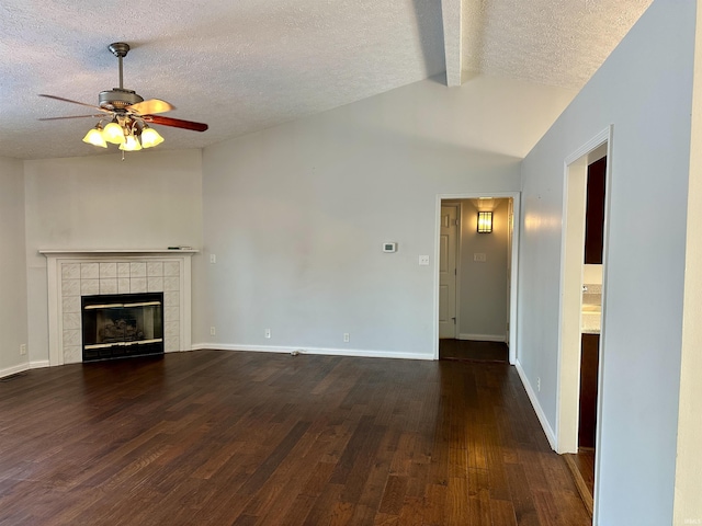 unfurnished living room featuring lofted ceiling with beams, ceiling fan, a textured ceiling, dark hardwood / wood-style flooring, and a tiled fireplace