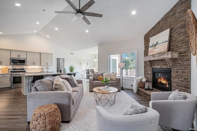 living room featuring ceiling fan, sink, a brick fireplace, high vaulted ceiling, and hardwood / wood-style floors