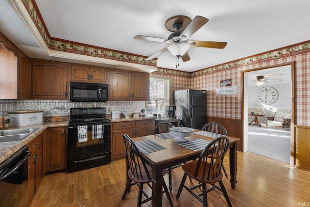 kitchen with sink, light wood-type flooring, stone countertops, and black appliances