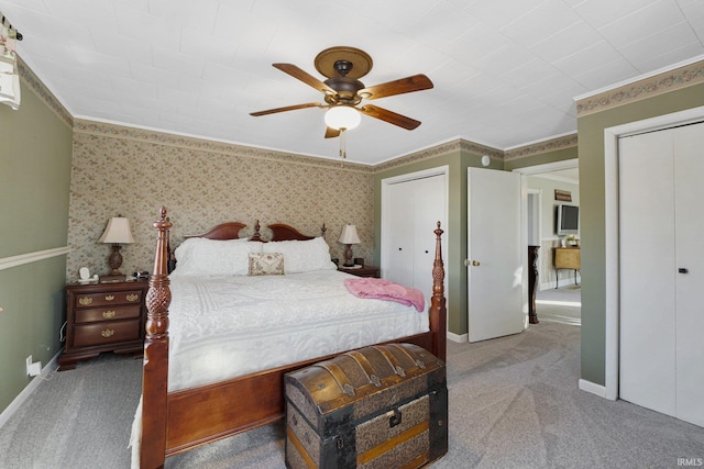 carpeted bedroom featuring ceiling fan, crown molding, and two closets