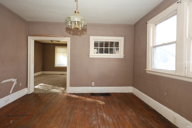 unfurnished dining area featuring a notable chandelier and dark hardwood / wood-style flooring