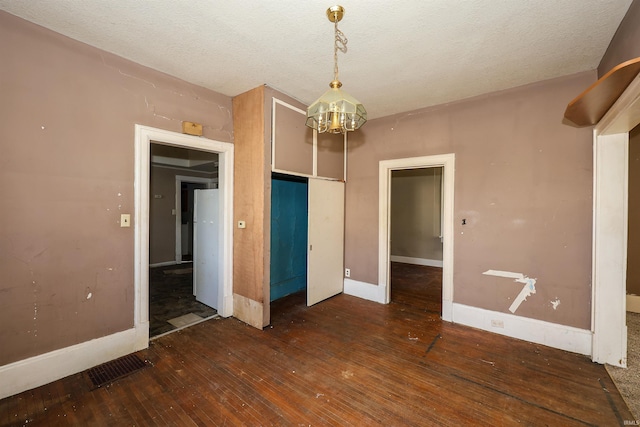 unfurnished bedroom featuring a notable chandelier, dark hardwood / wood-style floors, and a textured ceiling