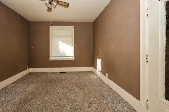 carpeted empty room featuring ceiling fan and a textured ceiling