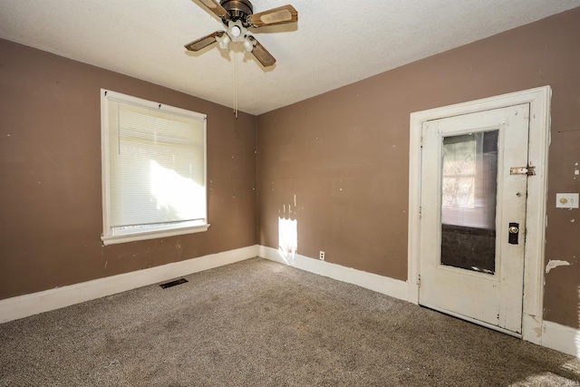 carpeted empty room with ceiling fan and a textured ceiling