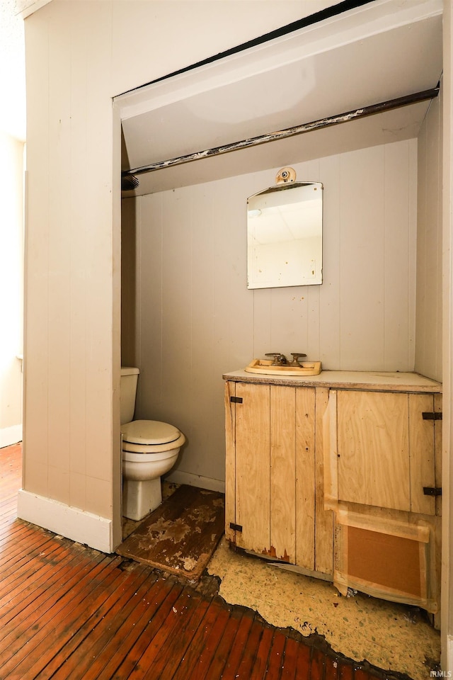 bathroom with toilet, wood-type flooring, and wooden walls