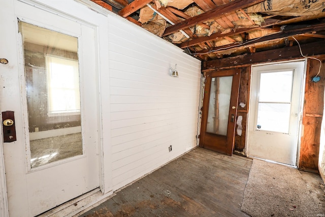 foyer with a wealth of natural light, wooden walls, and dark wood-type flooring