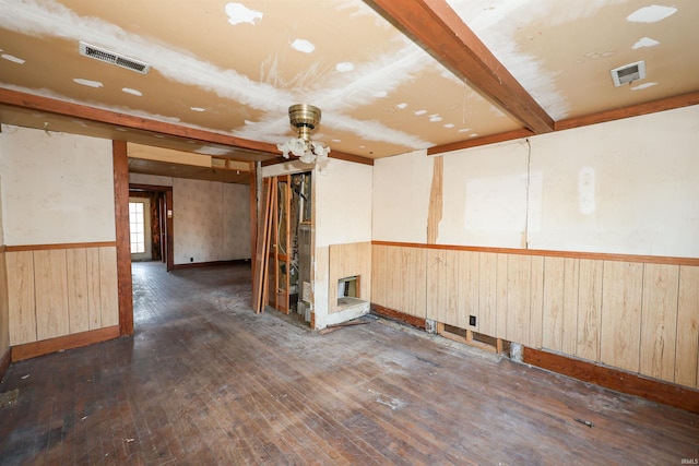 unfurnished room featuring a multi sided fireplace, wooden walls, ceiling fan, and dark wood-type flooring