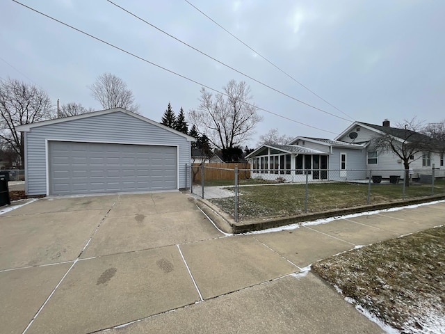 single story home featuring an outbuilding, a garage, a front lawn, and a sunroom