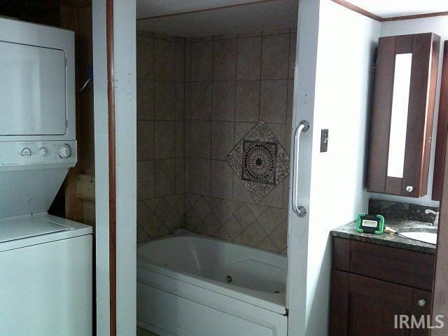 bathroom with a washtub, vanity, and stacked washing maching and dryer