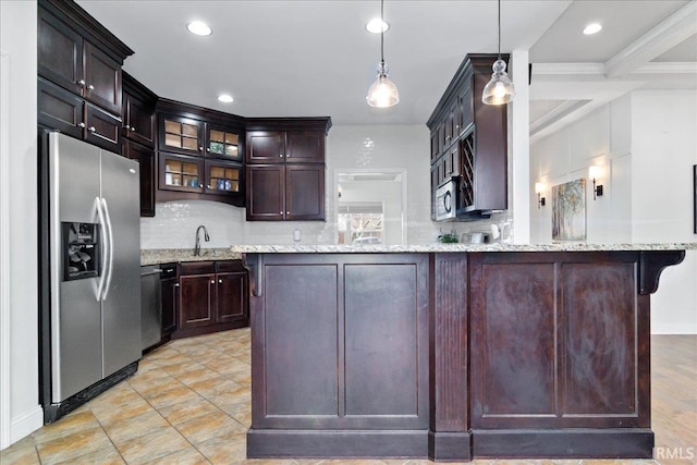 kitchen featuring light stone countertops, stainless steel appliances, kitchen peninsula, decorative light fixtures, and decorative backsplash