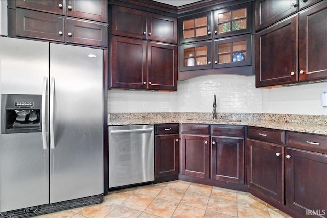 kitchen with light stone countertops, decorative backsplash, stainless steel appliances, and sink