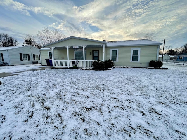 snow covered back of property with a porch