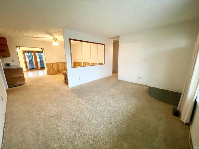 empty room featuring ceiling fan, light colored carpet, a textured ceiling, and wooden walls