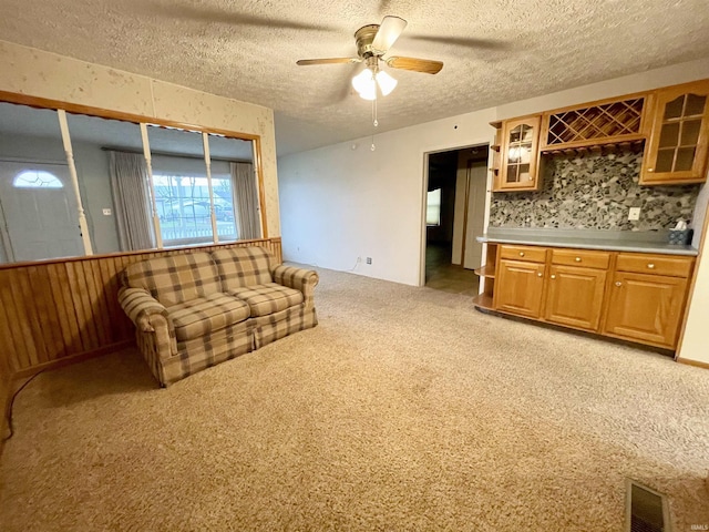 living room featuring a textured ceiling, light colored carpet, and ceiling fan