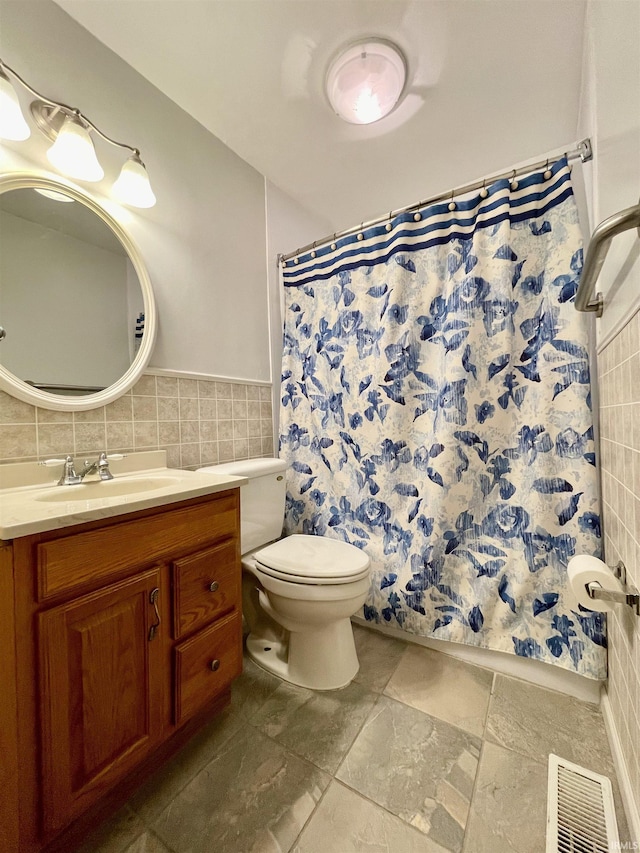 bathroom featuring a shower with shower curtain, vanity, toilet, and tile walls