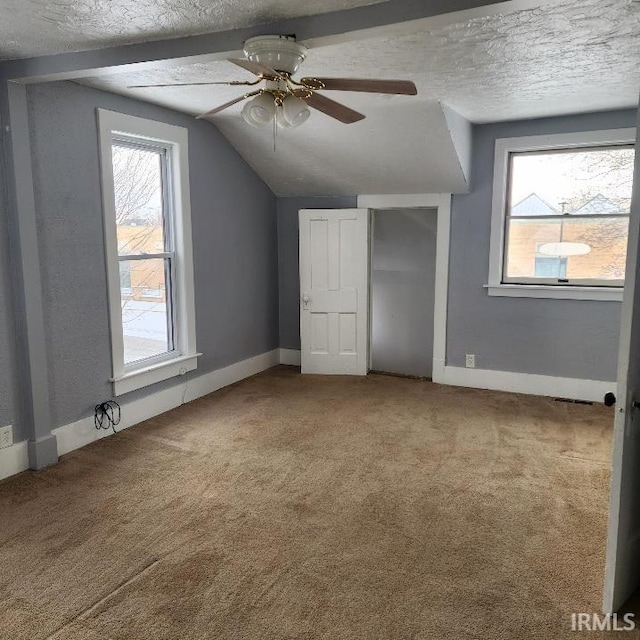 additional living space featuring a textured ceiling, ceiling fan, carpet, and vaulted ceiling