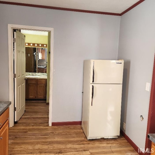 kitchen with white fridge, sink, light hardwood / wood-style floors, and crown molding