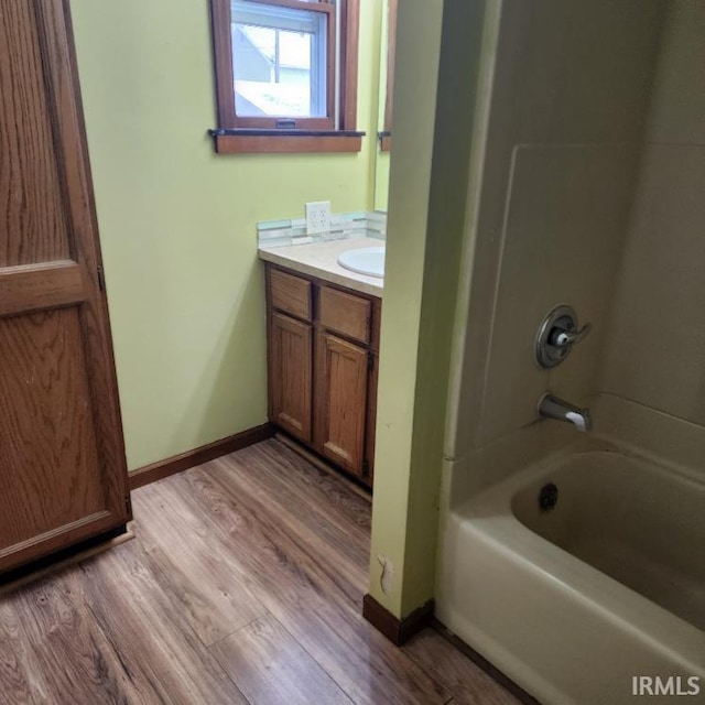 bathroom with bathtub / shower combination, hardwood / wood-style floors, and vanity