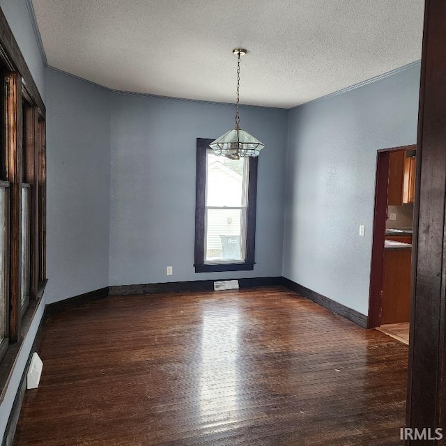 spare room featuring crown molding, dark hardwood / wood-style floors, a textured ceiling, and a notable chandelier