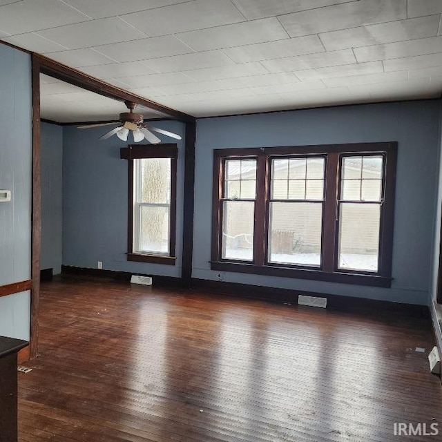 spare room with ceiling fan, beamed ceiling, and dark wood-type flooring