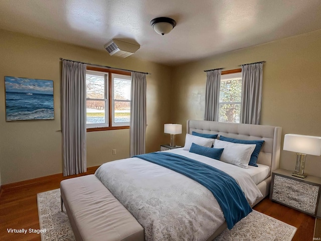 bedroom featuring multiple windows and dark hardwood / wood-style flooring