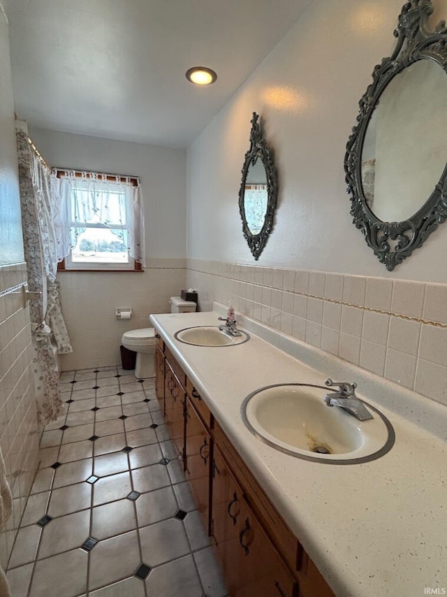 bathroom with tile patterned floors, vanity, tile walls, and toilet