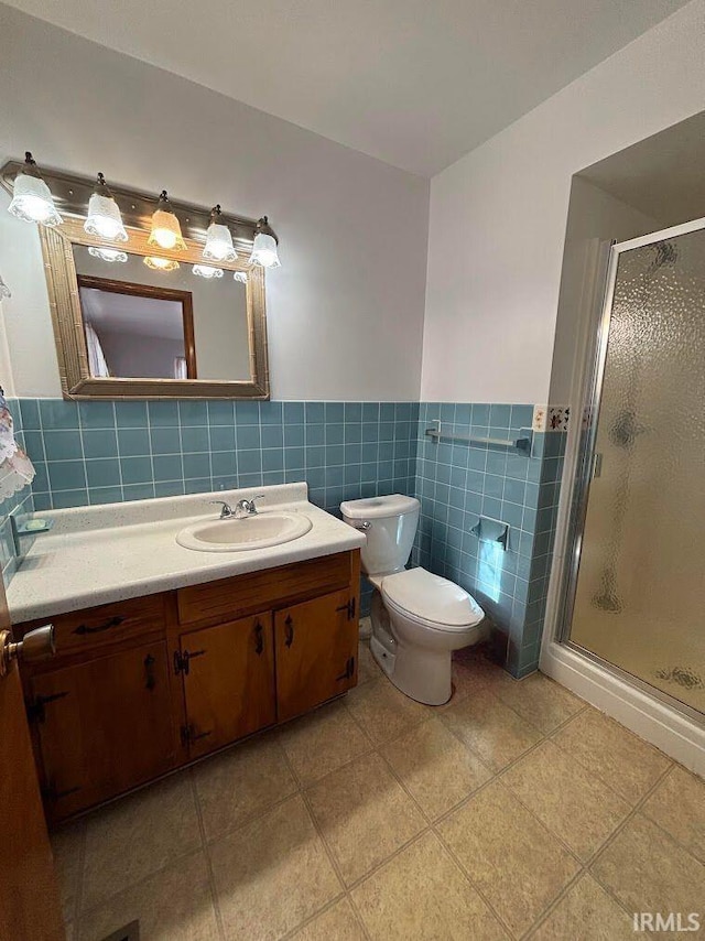 bathroom with vanity, tile patterned flooring, toilet, tile walls, and walk in shower