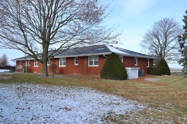 view of snowy exterior featuring central air condition unit and a yard